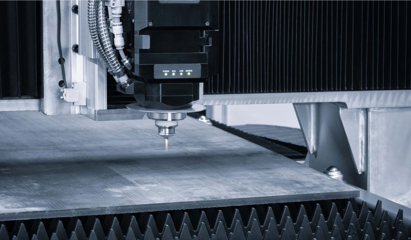 Close-up view of a laser cutting machine's head over a metal sheet, with precision focus on the cutting process in a clean and modern industrial setting