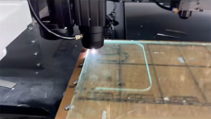 Laser cutter in operation, etching a rectangular design on a glass sheet