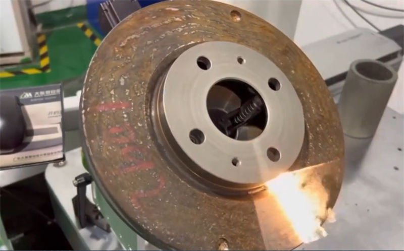 A laser beam precisely targeting and removing rust from a metal disc
