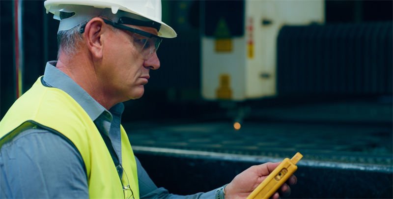 Monitoring Laser Cutting Process Technician using a handheld device to monitor laser cutting.