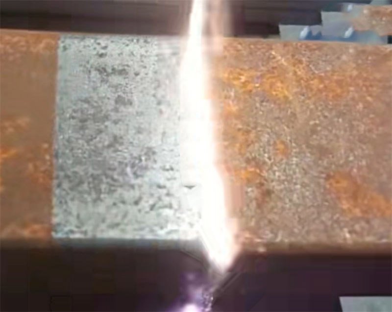 A laser beam removing rust from a steel pipe surface