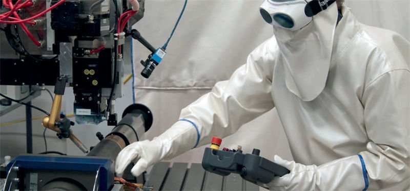 A technician in protective gear using a robotic system for laser rust removal