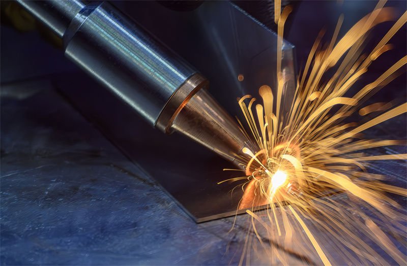 A laser welding gun emitting bright sparks while welding a thin metal sheet