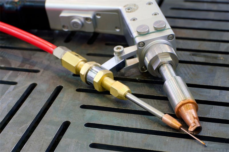 Close-up of a handheld laser welding gun set up on a workstation with precision equipment
