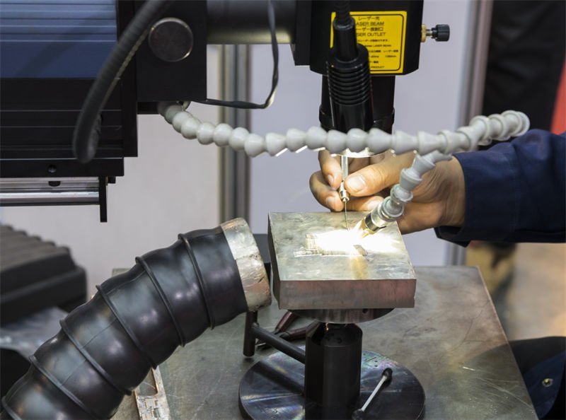 Precision Laser Welding in Action A technician using a laser welding station to precisely weld a small metallic component