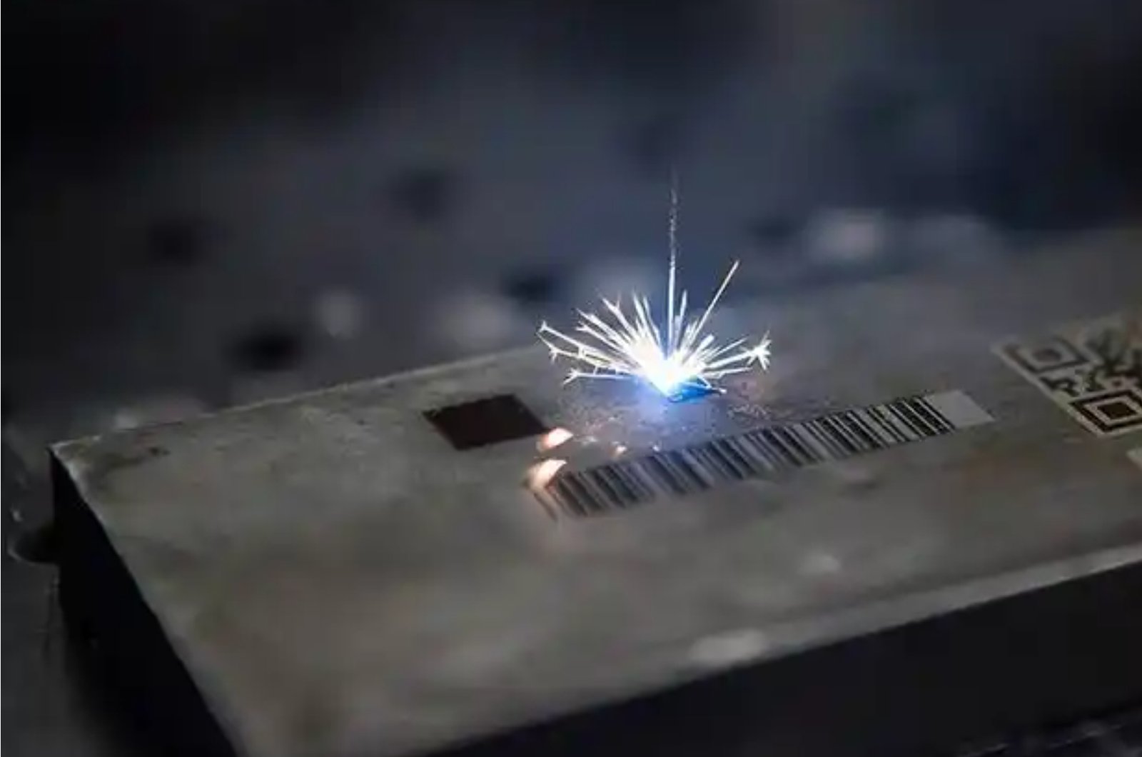 Laser marking a barcode on a metal surface with visible sparks