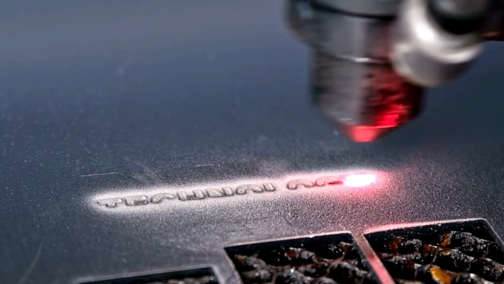 Lasergravur von Text auf einer Metalloberfläche mit einem fokussierten roten Laserstrahl