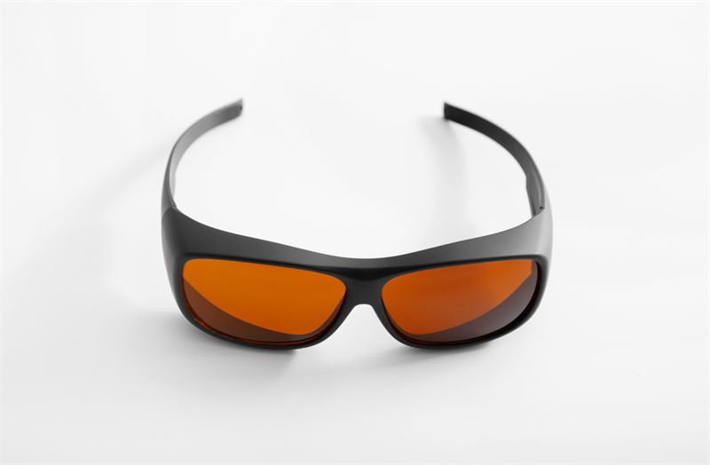 A pair of black-framed laser safety glasses with orange-tinted lenses on a white background