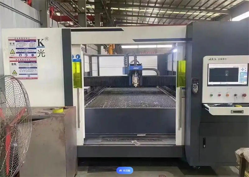 A laser cutting machine with an enclosed structure, a control panel, and a ventilation fan in an industrial workshop