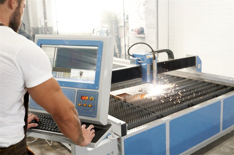 An operator monitoring a CNC plasma cutting machine at work.