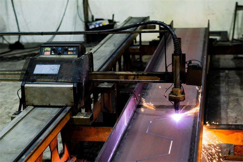 A plasma cutting machine performing precise cuts on a metal beam in an industrial setting