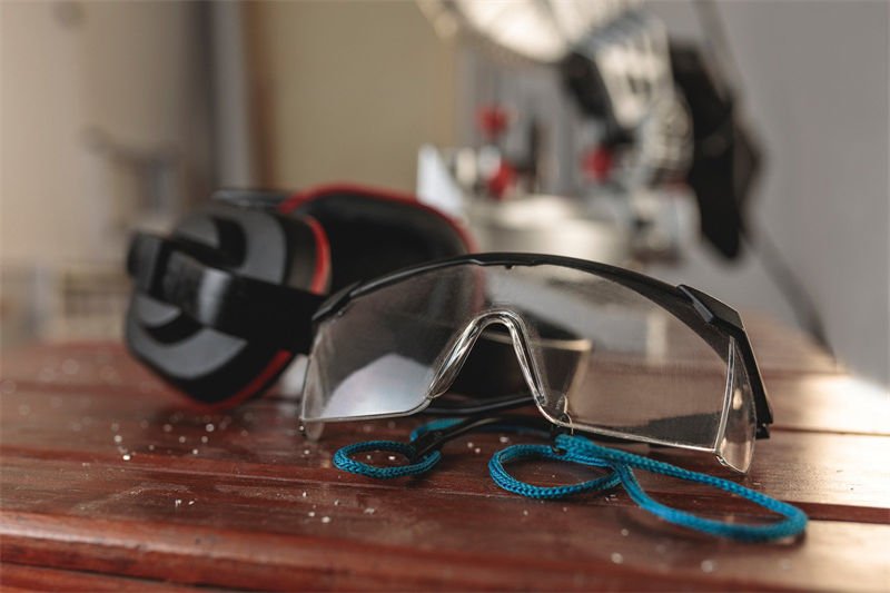 Protective Gear for Laser Operations Laser safety glasses with a blue strap placed on a wooden surface, with ear protection equipment in the background