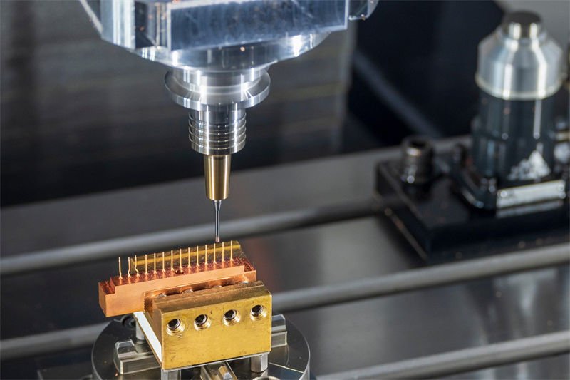 A CNC milling machine working on a copper component with precise detailing