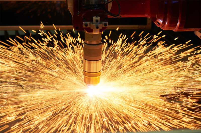 A plasma CNC cutting machine emitting an intense burst of sparks as it cuts through metal.