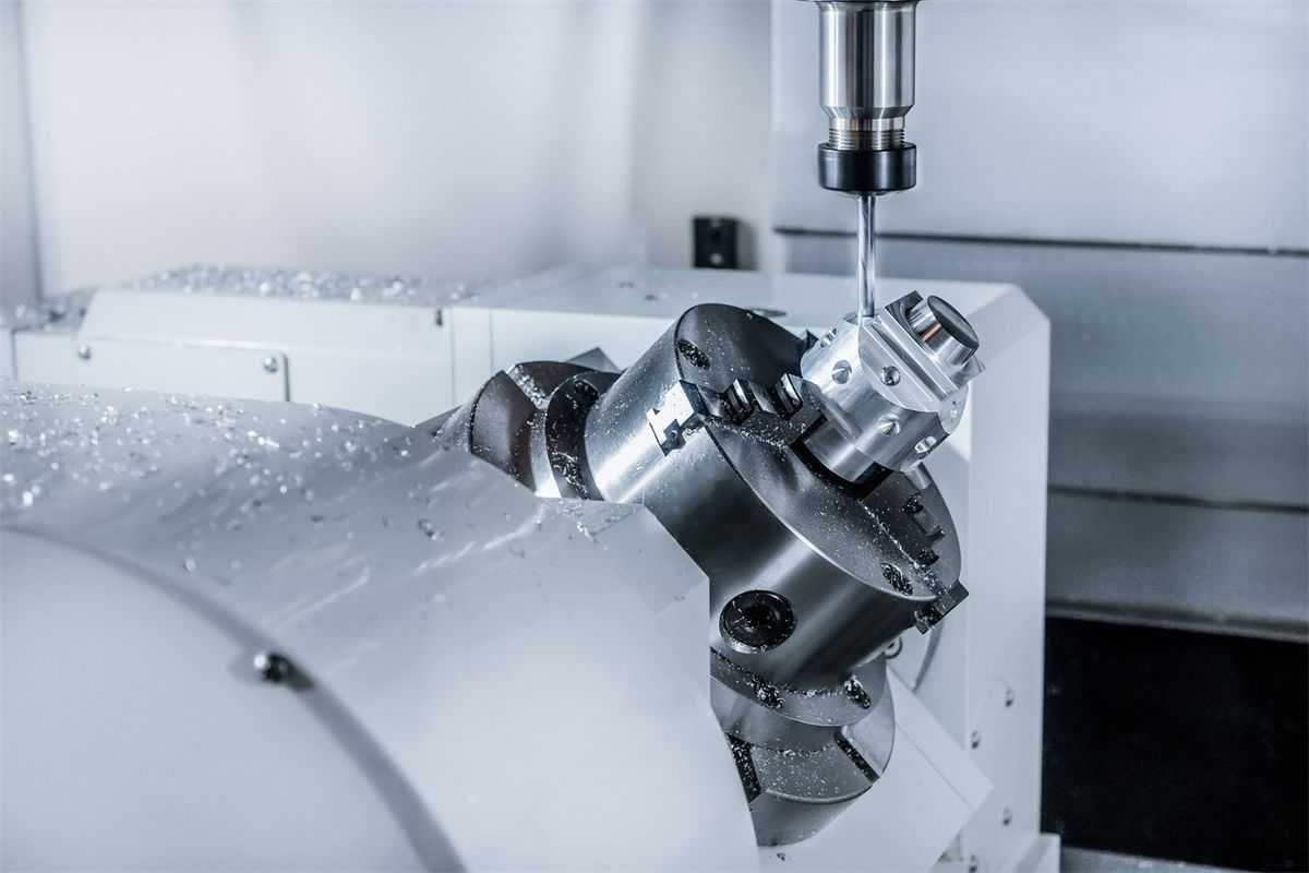 A technician wearing safety glasses and a red uniform performing maintenance on a CNC milling machine