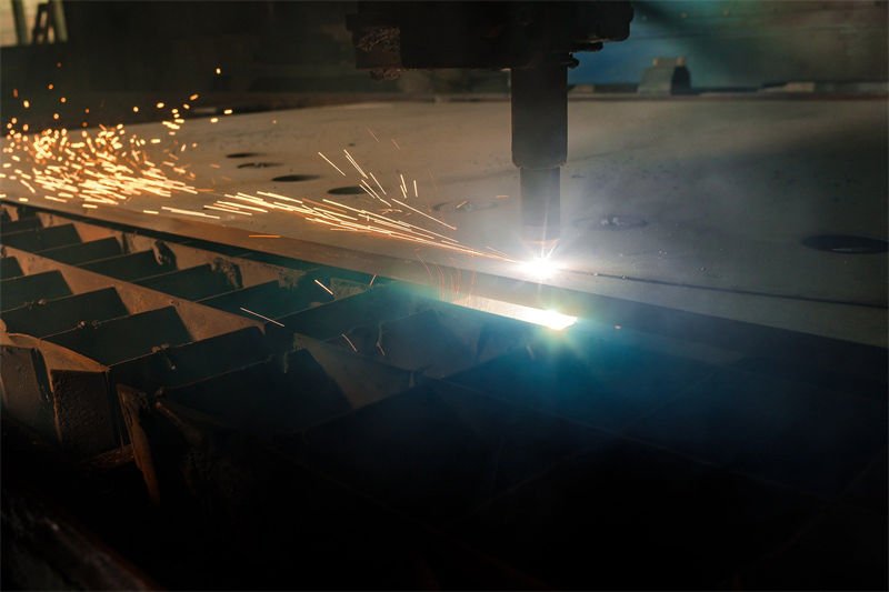 Bright sparks flying from a plasma cutter as it slices through a thick steel plate