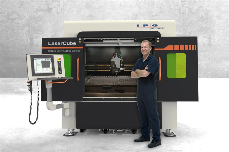 An engineer standing next to an IPG LaserCube fiber laser cutter with its doors open