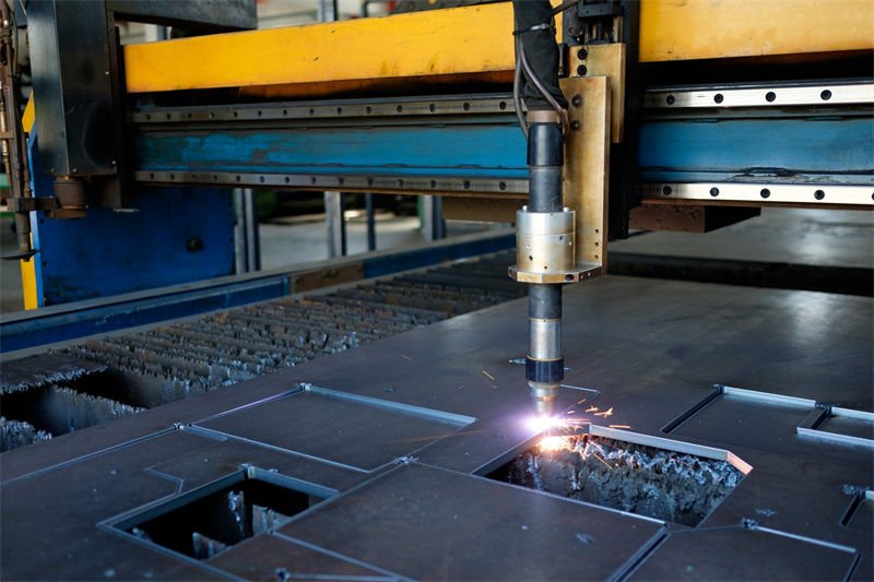 A close-up view of a plasma cutting torch in operation on a metal fabrication table