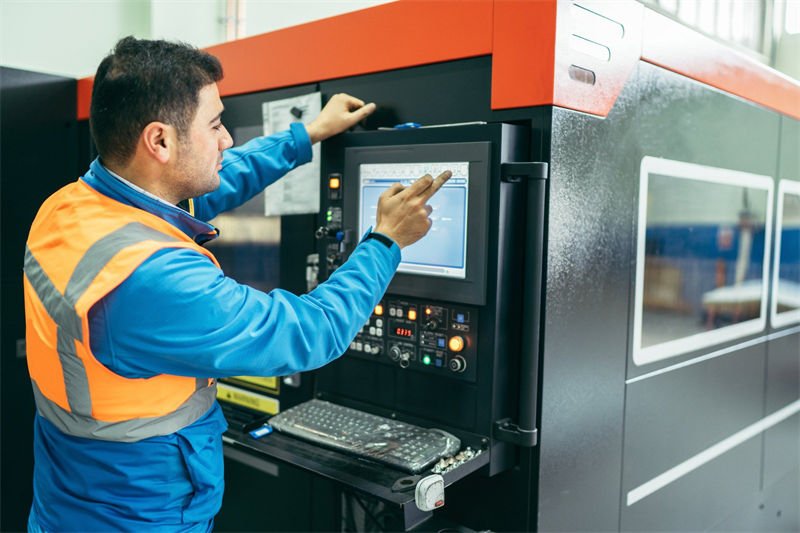 A machine operator using a control panel on a laser cutting machine