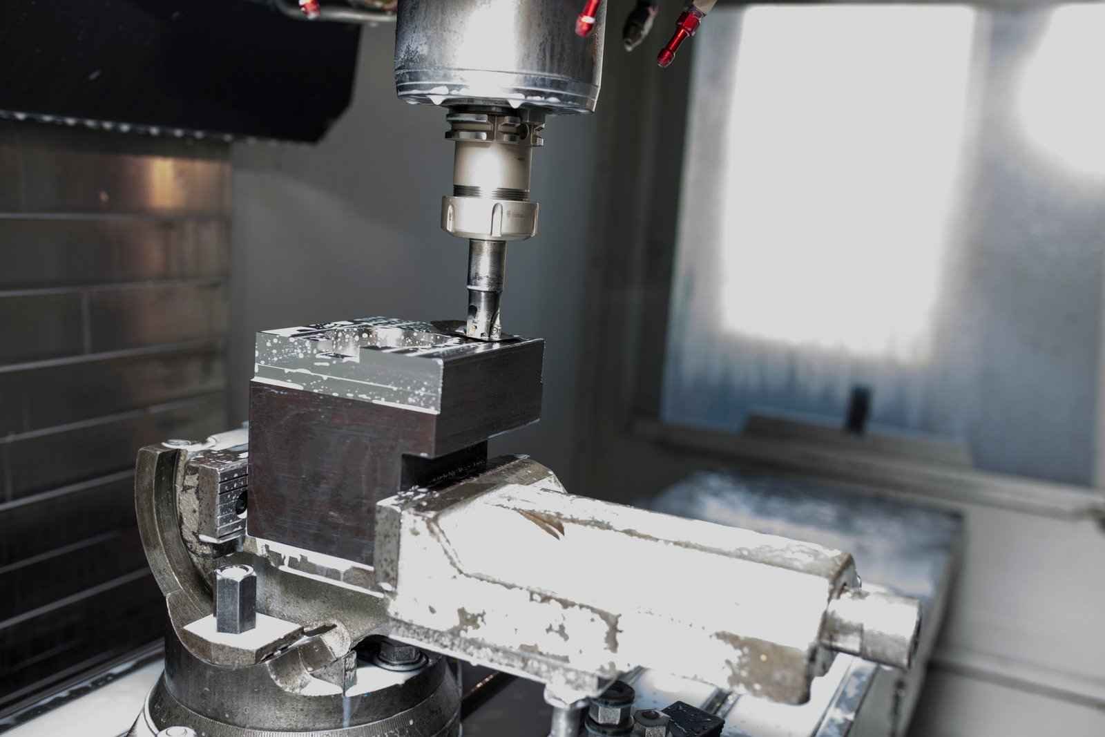 A milling machine processing a rectangular metal workpiece with a precision tool