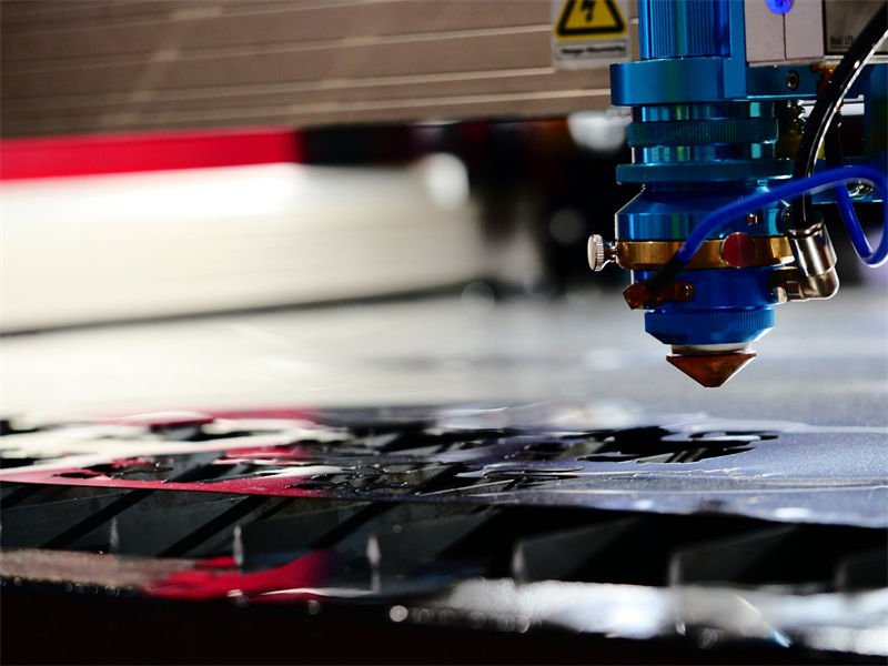 Close-up of a laser cutter head cutting detailed designs on metal