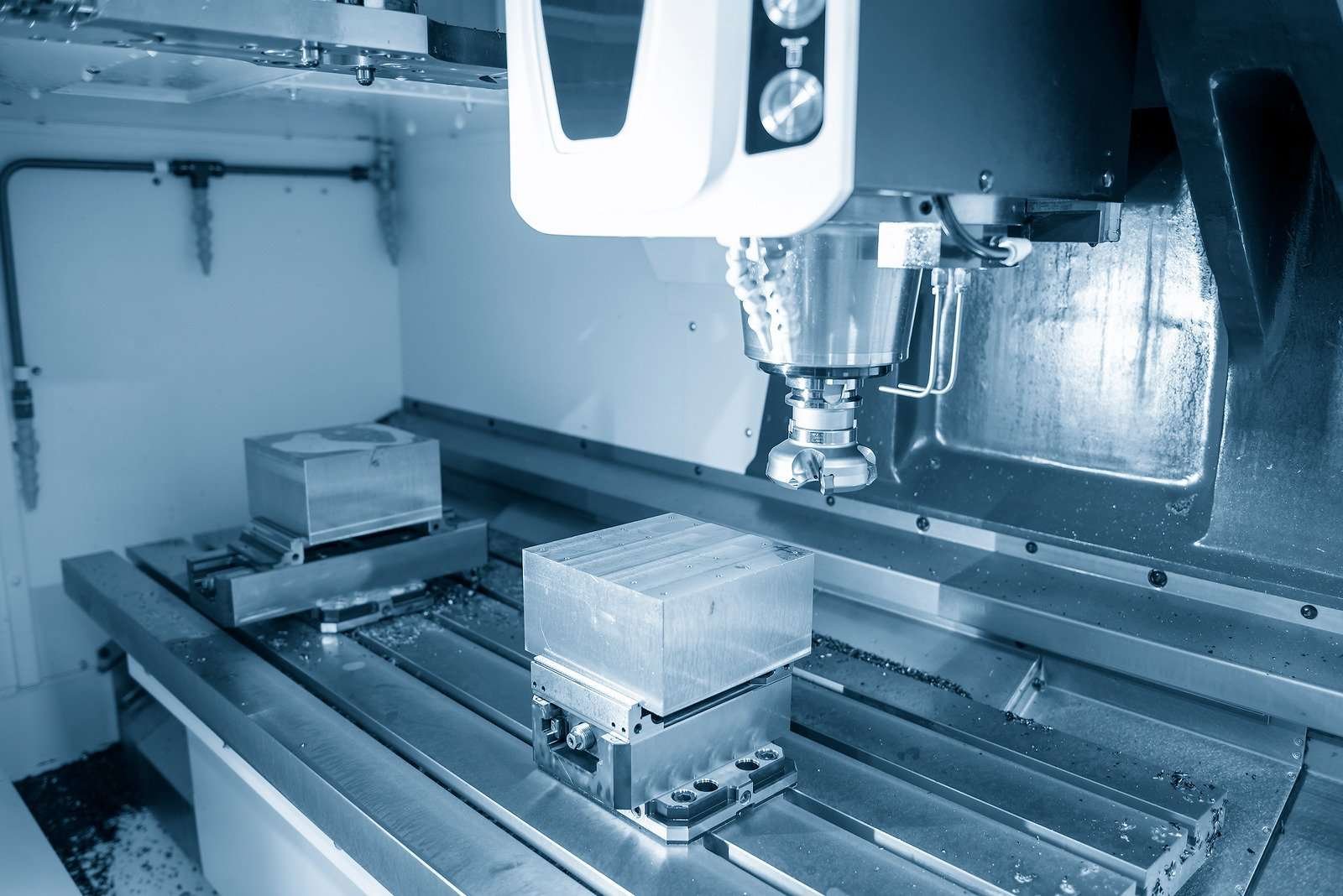 Close-up view of a CNC milling machine during operation, with a metallic workpiece secured on the machine bed