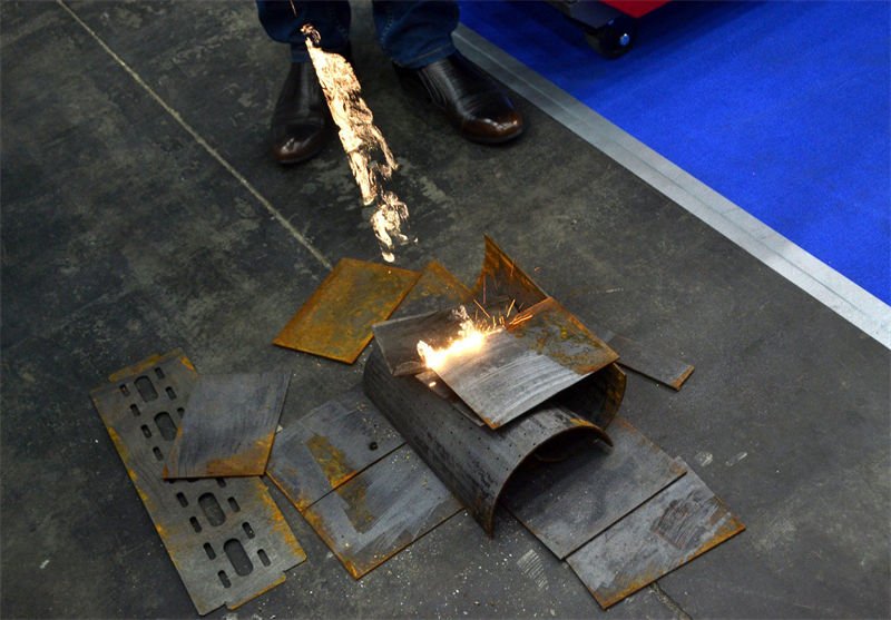 A laser cleaning demonstration removing rust from various metal parts on a factory floor