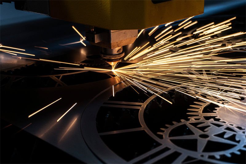 A laser cutting machine in action, slicing through a galvanized steel sheet, with sparks flying