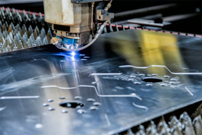 A laser cutter smoothly engraves designs into a shiny aluminum sheet.