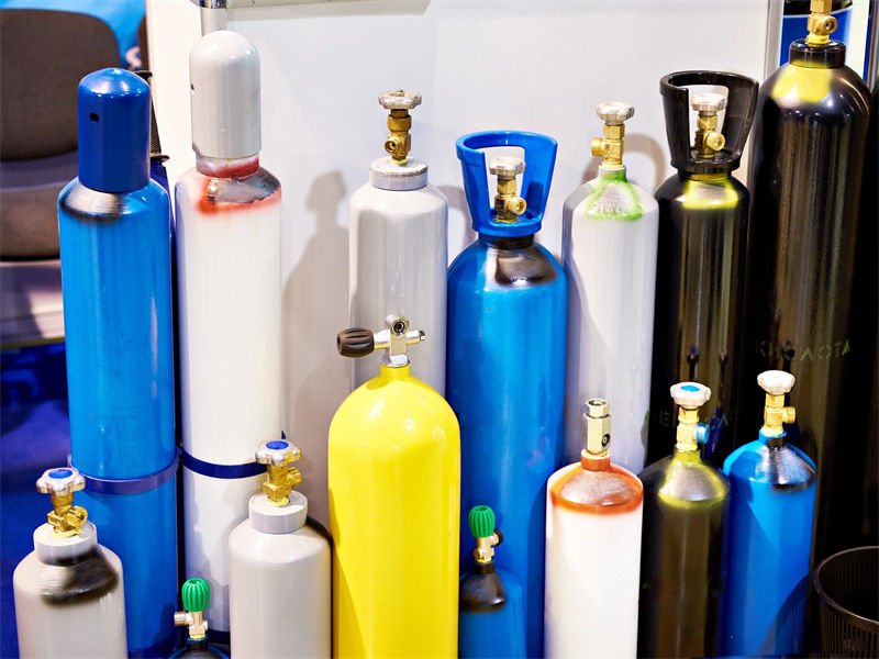 Assorted gas cylinders with different colored tanks and valves