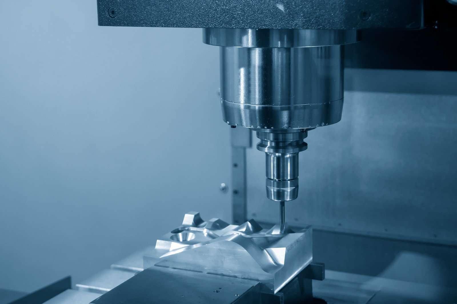 A CNC milling machine processing a complex workpiece with rectangular and trapezoidal features