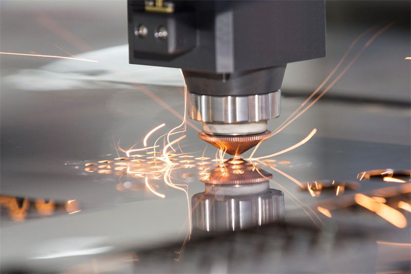 A laser cutter generating sparks as it engraves a metallic surface