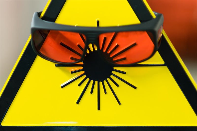 Essential Laser Safety Gear Laser safety glasses resting on a hazard sign indicating the need for protective eye wear during laser operations