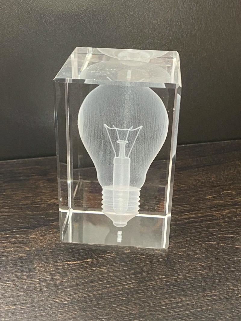 3D laser-engraved light bulb design inside a transparent glass block