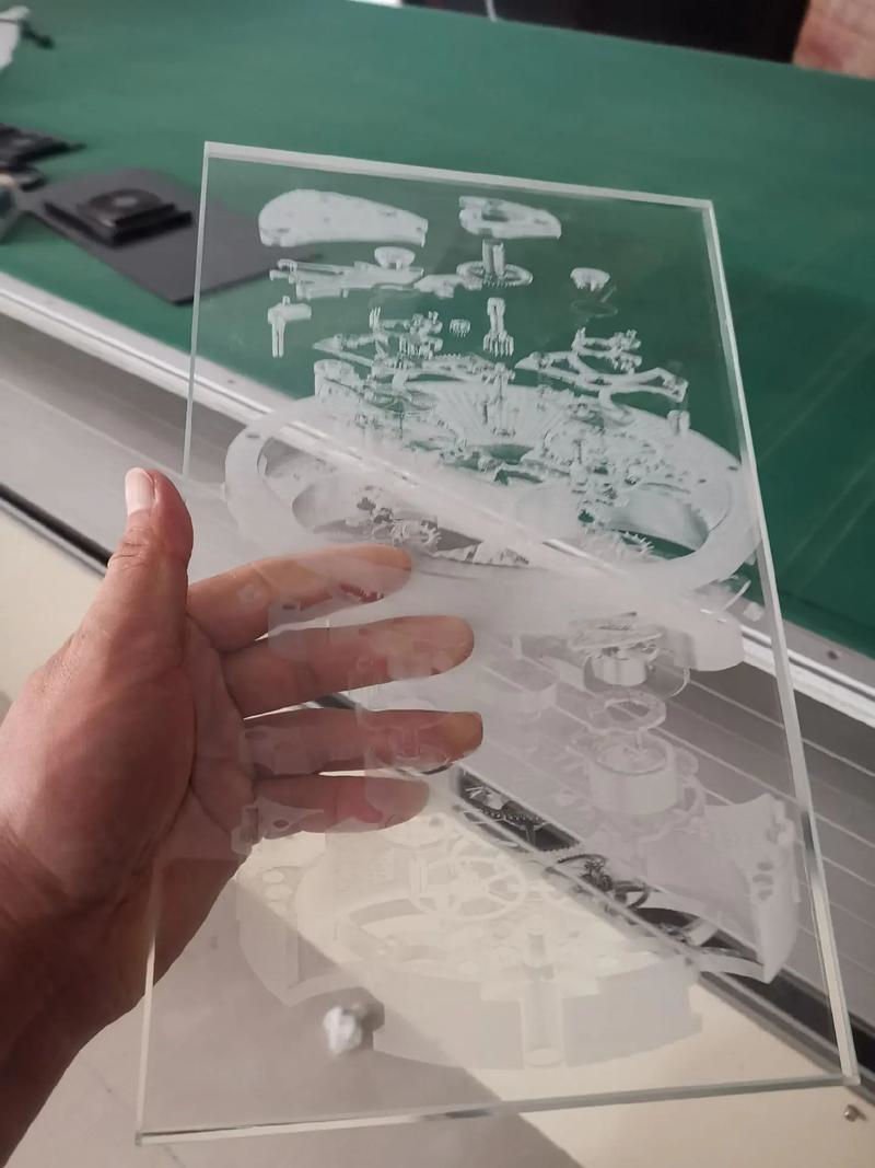 Hand holding a piece of glass engraved with intricate designs using laser engraving technology