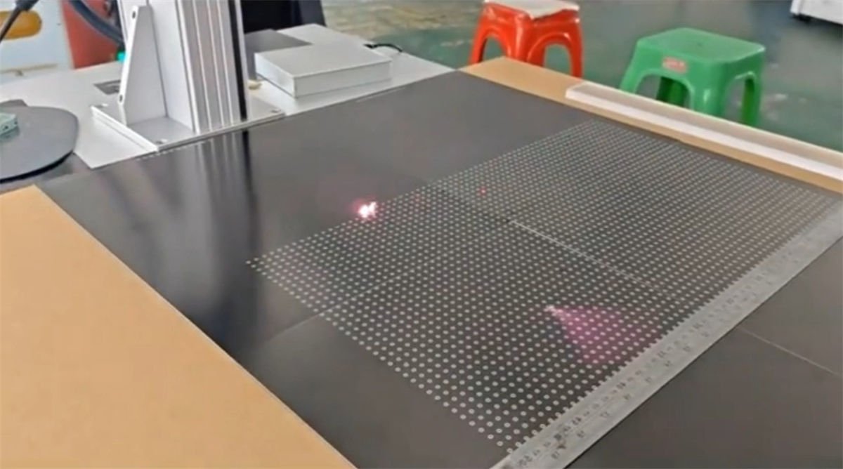 Laser marking machine engraving a grid pattern on a stone surface