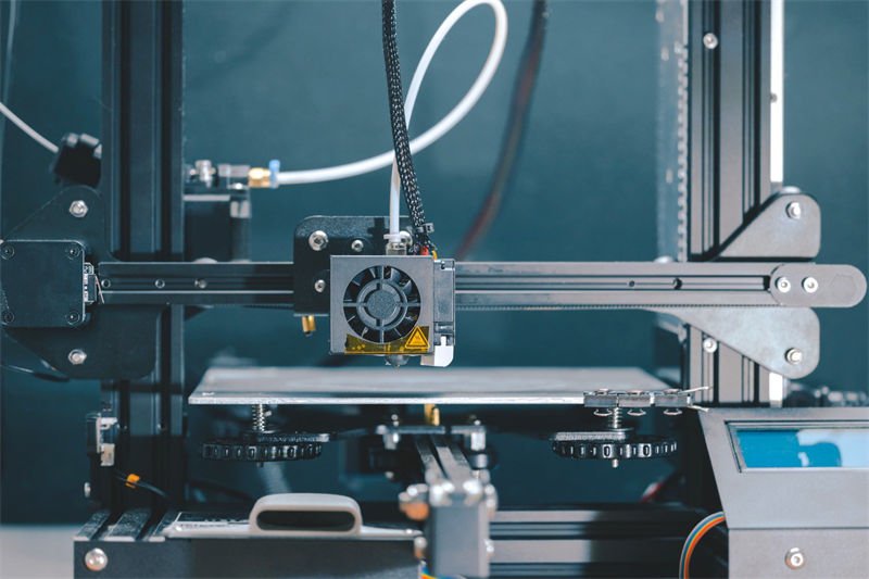 A close-up of a 3D printer with its nozzle and platform, ready for printing