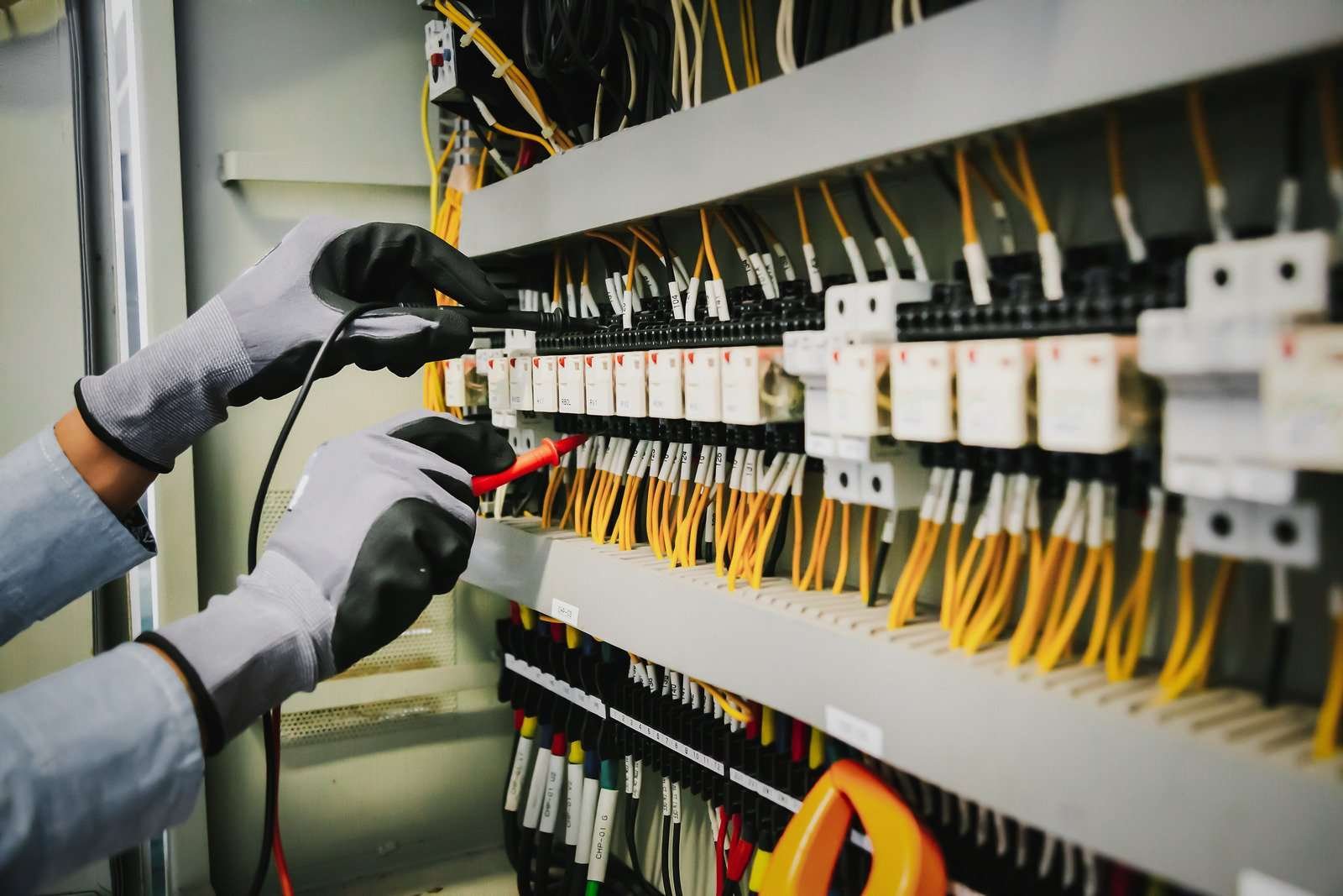  Technician using testing equipment to examine electrical wiring in a control panel