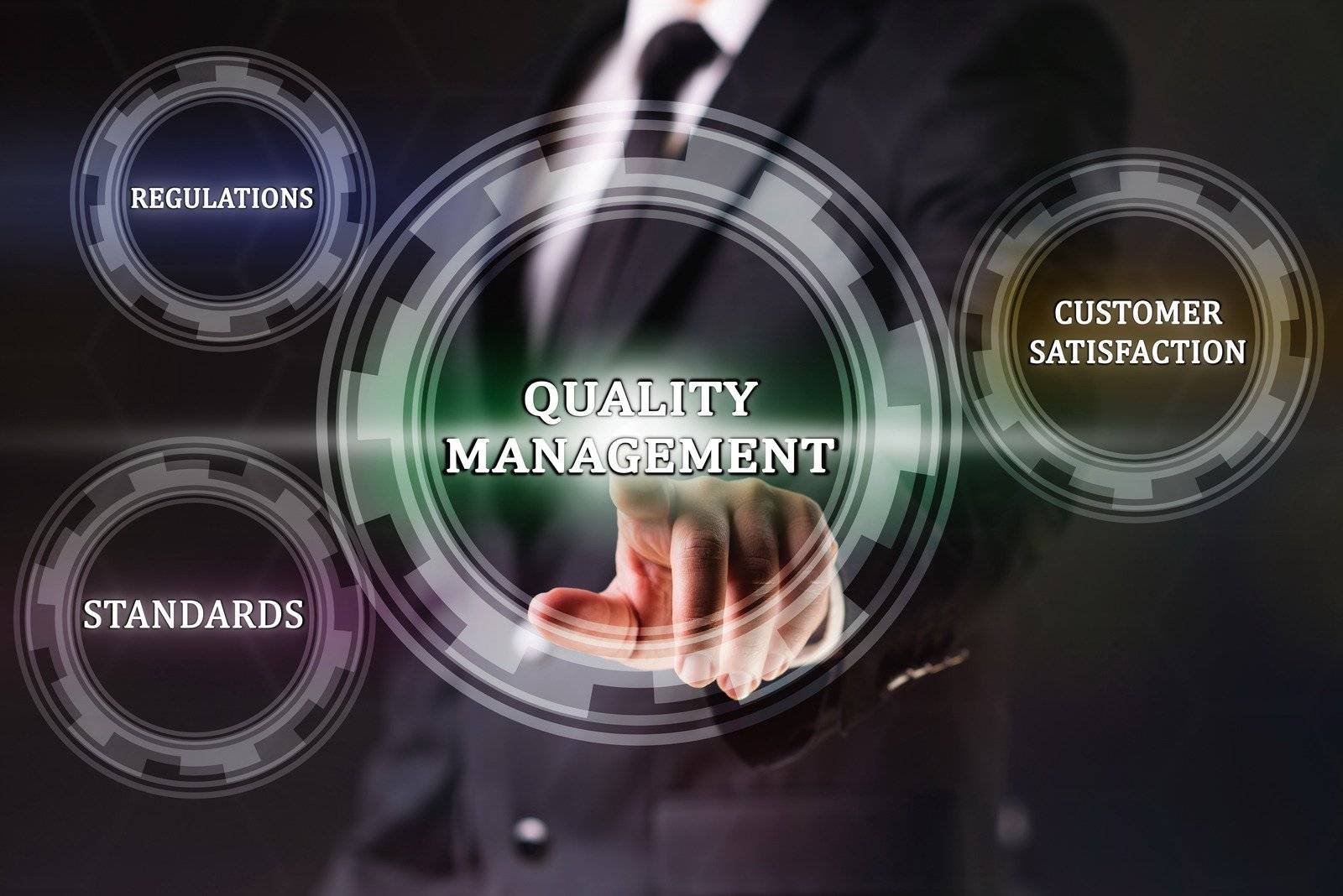 Business professional interacting with a virtual interface displaying "Quality Management" and related aspects like regulations, standards, and customer satisfaction