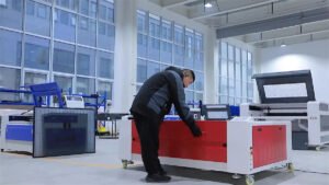 A technician working on a CO2 laser cutting and engraving machine in a modern factory