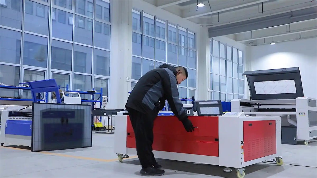 A technician working on a CO2 laser cutting and engraving machine in a modern factory